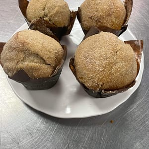 Four plated, sugar-topped muffins