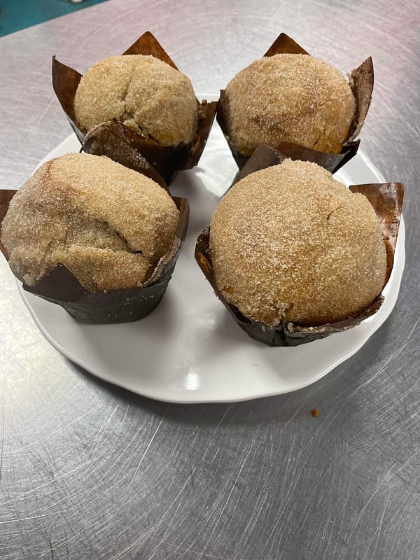 Four plated, sugar-topped muffins